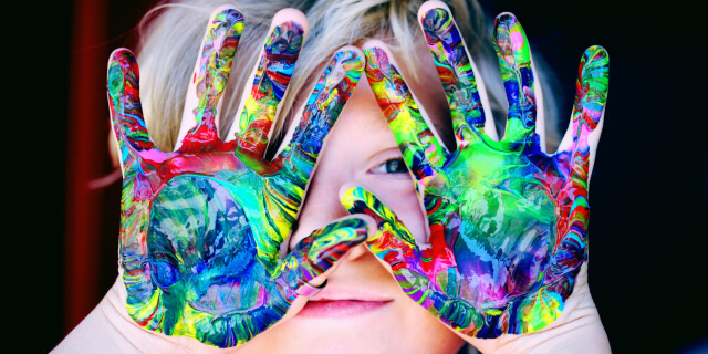 A child shows their colorful painted hands